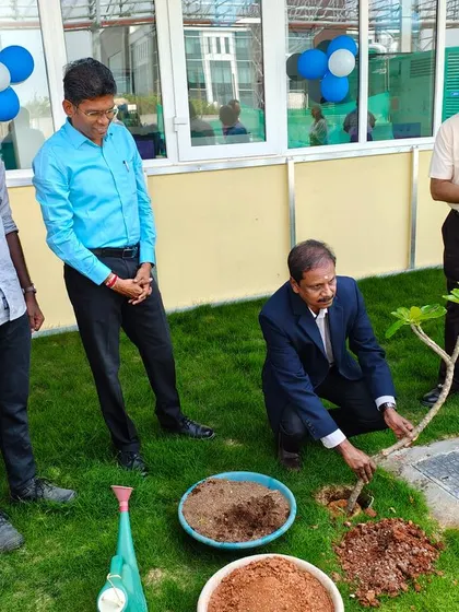 A client representative carefully plants a new tree on their corporate campus, marking the successful completion of our landscaping work.