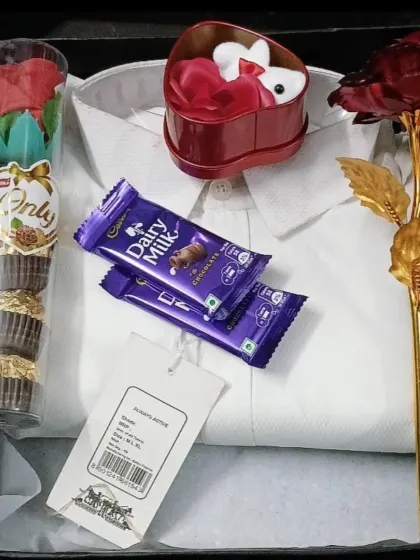 A sweet and simple gift box containing a white shirt, Ferrero Rocher chocolates, and decorative roses, perfect for any celebration.