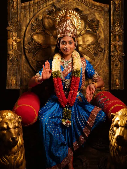 A divine Devi costume for kids or adults, featuring a beautiful blue and gold saree, a crown, and a garland, set on a majestic throne.