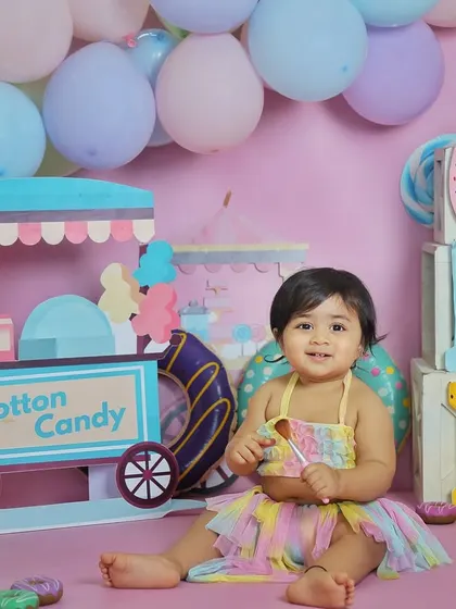 A sweet portrait from a candyland-themed first birthday shoot. The pastel colors, donut props, and cotton candy stand create a whimsical and fun atmosphere.