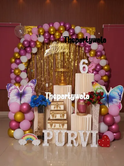 A glamorous butterfly theme with a gold shimmer backdrop and a pink and gold balloon arch.