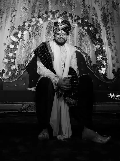 A timeless black and white portrait of the groom. This classic style emphasizes his expression and the rich textures of his wedding attire, creating a powerful and elegant image.