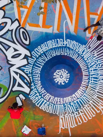 An aerial shot of me and another artist working on the massive calligraffiti circle at the Bandra Skatepark. This shows the scale and teamwork involved in large public art projects.