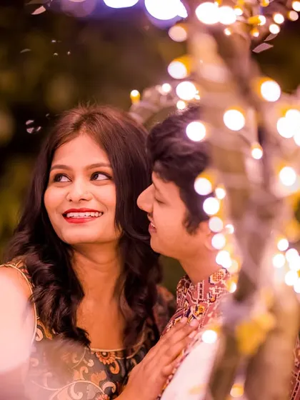 A close-up shot capturing a sweet, whispered secret amidst the warm glow of fairy lights. These are the real, unscripted moments I love to photograph.