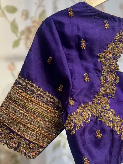 A side view of the simple purple blouse, highlighting the beautiful band of embroidery on the sleeve.