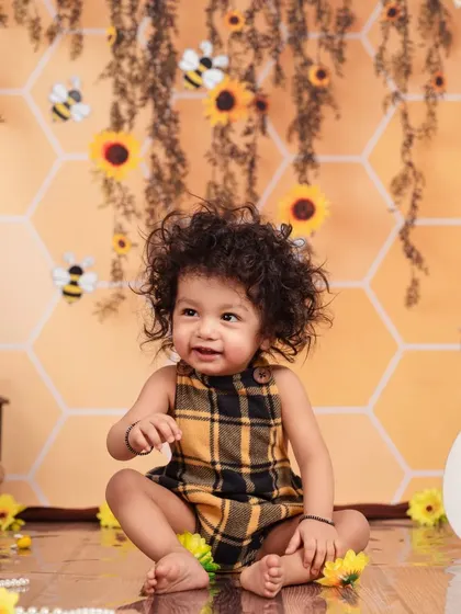 With the most adorable curly hair, this little bee is sitting pretty in our sunflower-filled studio setup.
