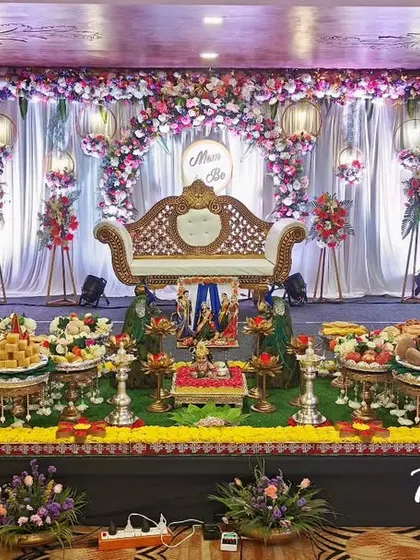 A complete baby shower setup with a floral arch, an ornate throne, and a long, beautifully arranged display of offering plates.