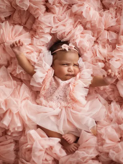 A big stretch! Even when they're not perfectly posed, these natural movements make for such adorable and authentic photographs. This little girl is waking up from her nap in a sea of pink ruffles.