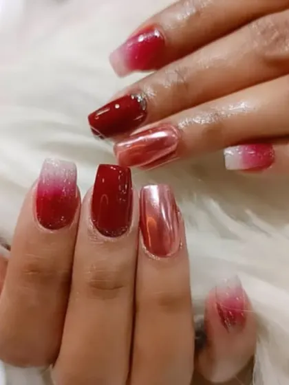 A festive red set featuring a mix of ombré, glitter, and a striking red chrome accent nail.