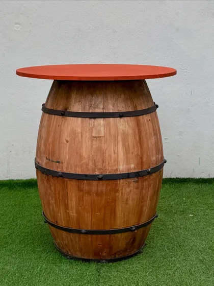 We offer customizable tabletops for our barrel tables. This one features a vibrant orange top, adding a pop of color to the rustic wood.