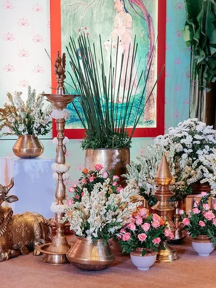 Traditional brass elements like the Nandi statue and tall diyas (lamps) are central to our South Indian decor. They are surrounded by fresh flowers, adding a touch of divinity and cultural richness.