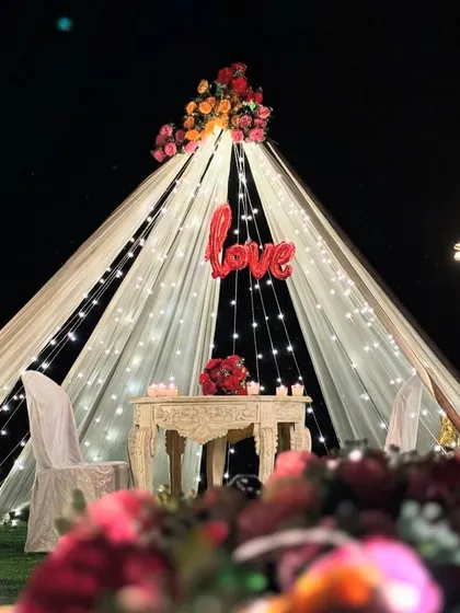 Another angle of the 'Love' proposal tent, showing the surrounding floral arrangements and lanterns that add to the romantic setting.