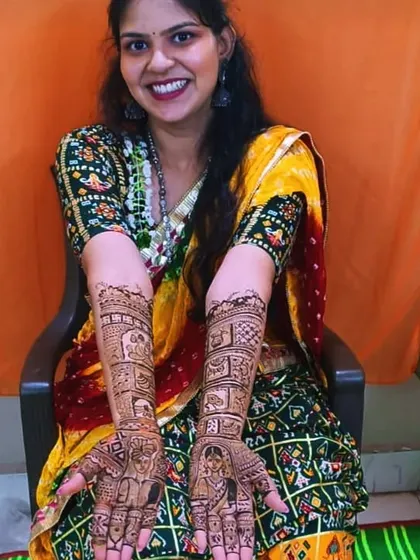 A very happy bride in traditional attire, proudly displaying her full portrait mehandi.