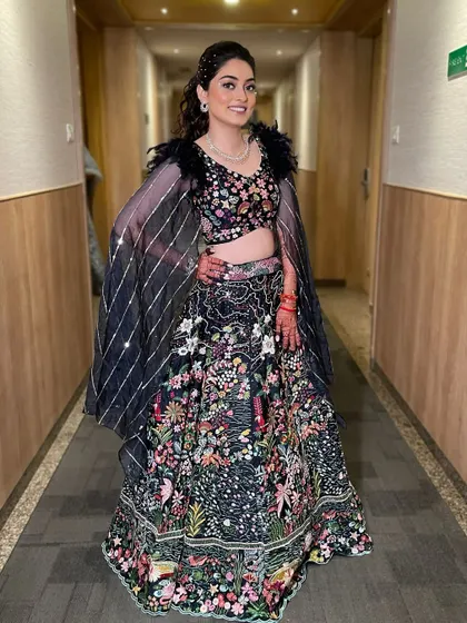 A full-length view of the bride, ready for her Sangeet. The entire look, from the feathered blouse to the sparkling makeup, is pure elegance.