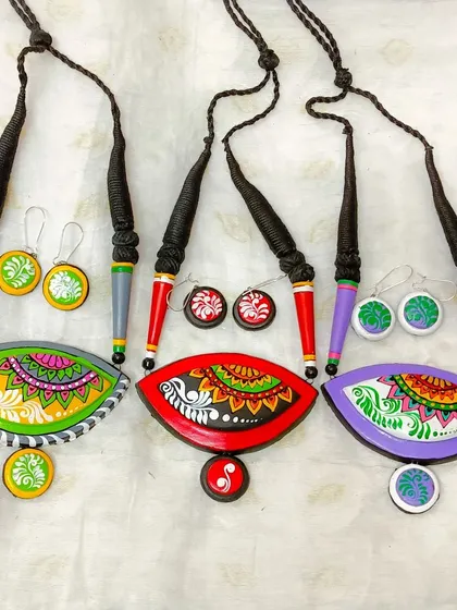 A display of the various color options available for the artistic fish-eye shaped necklace.