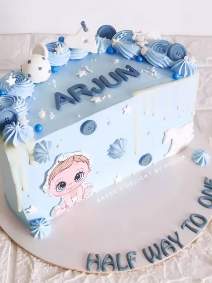 Halfway to one! This sweet half-birthday cake in baby blue is decorated with cute buttons, stars, and a white chocolate drip, celebrating six months of happiness.