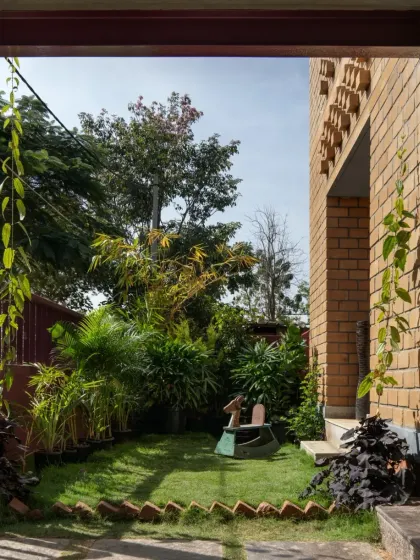 The garden of the Eesha residence, viewed from the shaded veranda. The home is designed to embrace its green surroundings, with creepers beginning to climb the sustainable CSEB walls.