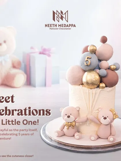 Sweet celebrations for a little one! This cake for a 5th birthday features two adorable teddy bears and a cascade of pastel and gold spheres.