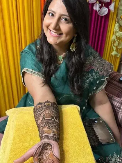 A happy client posing with her bridal mehendi, which features a bride portrait and elephant motifs. I provide home service for your comfort.