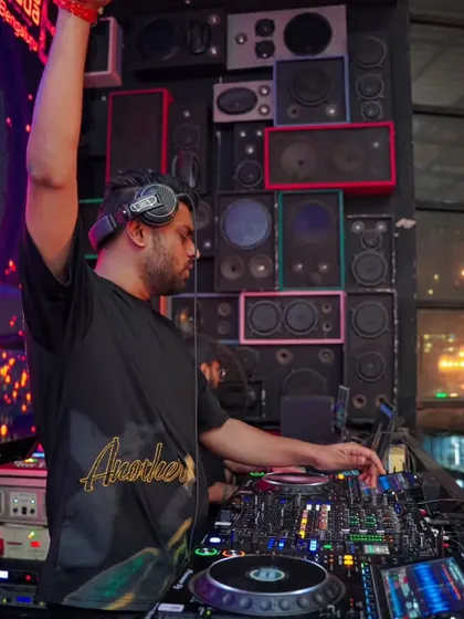 Raising a hand to connect with the crowd while mixing. It's these small moments of interaction that build a great party atmosphere.