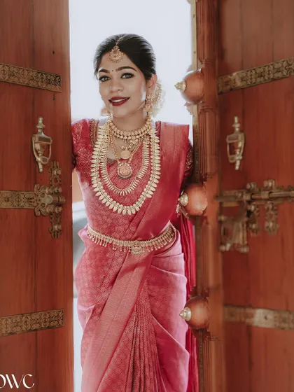 A welcoming smile from the bride as she peeks through traditional wooden doors.
