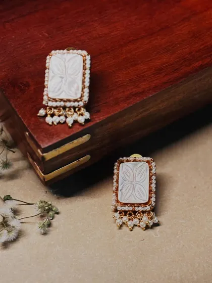 These elegant rectangular studs feature a carved mother-of-pearl center, framed by polki diamonds and finished with pearl drops.