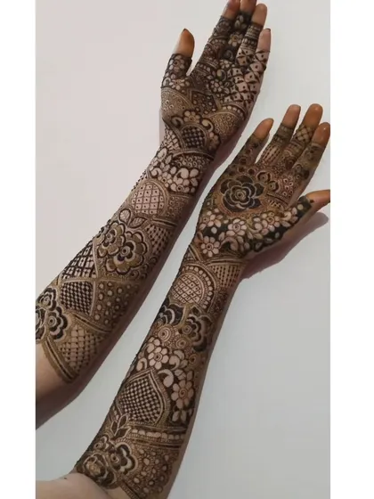 This full-arm design showcases a variety of patterns, from geometric grids on the wrist to floral work on the palm and fingers. It's a great example of a mixed-motif bridal style.