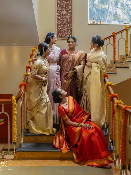 The bride sharing a laugh with her bridesmaids on the stairs, a candid moment of friendship before the wedding chaos begins.