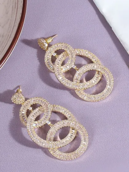A flatlay of sparkling, multi hoop earrings against a simple purple background. This shot is clean and modern, focusing on the unique design and brilliance of the stones.