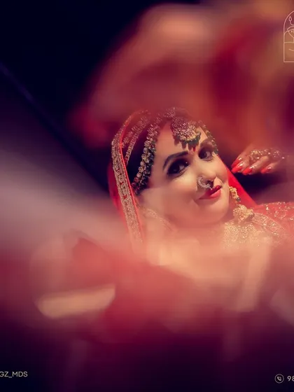 An artistic shot of a bride, viewed through a foreground blur, creating a dreamy and creative portrait.