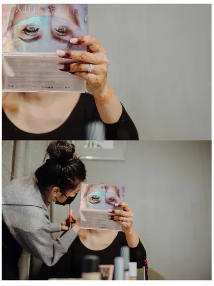 A creative shot of the bride's eye makeup being done, seen through the reflection of an eyeshadow palette.