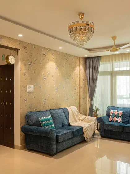 After: The same living room, completely revitalized with new wallpaper, elegant curtains, a statement chandelier, and reupholstered sofas for a luxurious feel.