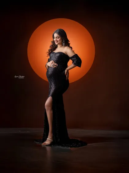 A modern and chic silhouette shot. The glowing orange circle provides a stunning contrast to the sparkling black gown, creating a bold and artistic statement.