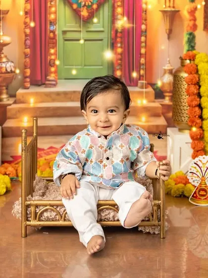 Seated on a miniature golden cot, this baby boy enjoys the festive atmosphere of our Diwali set. The vibrant colors and traditional decor create a magical scene.