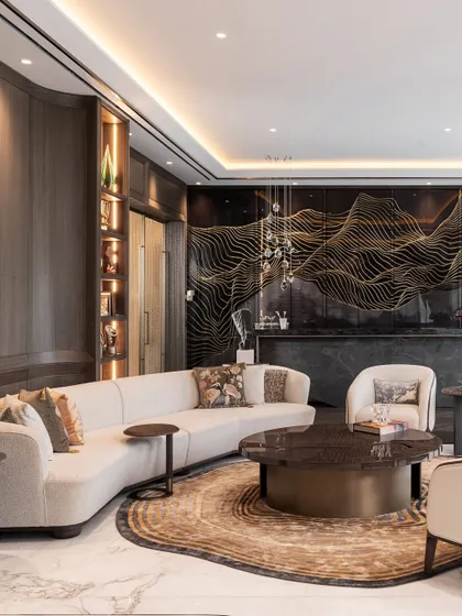 A curved sofa follows the organic shape of the custom rug in this lounge area, creating a sense of cohesive flow. The design showcases how bespoke furniture can be crafted to respond directly to the architectural elements and decor of a room.
