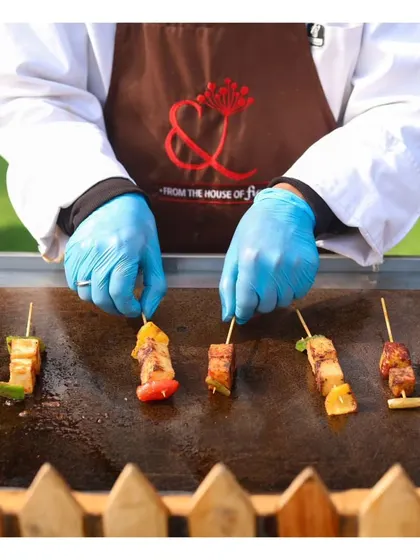 A chef grilling skewers of paneer and vegetables, a popular vegetarian option at our live barbecue stations.
