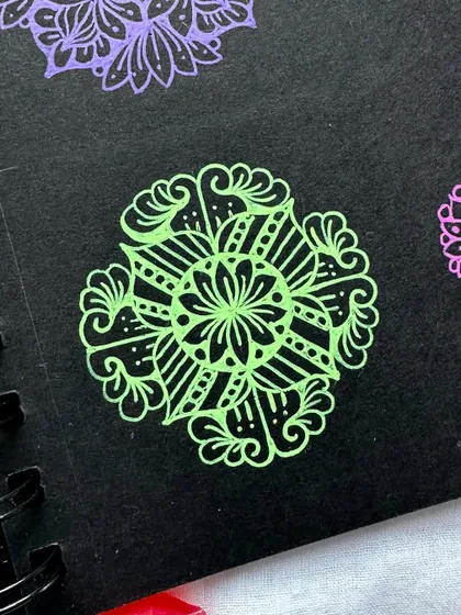 A close-up of a lime green mini mandala on black paper. Even a small, simple design can be incredibly striking with this technique.