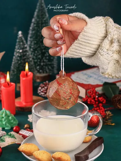 A creative shot of a chocolate bomb ornament being dipped into a glass of milk, capturing a magical holiday moment.