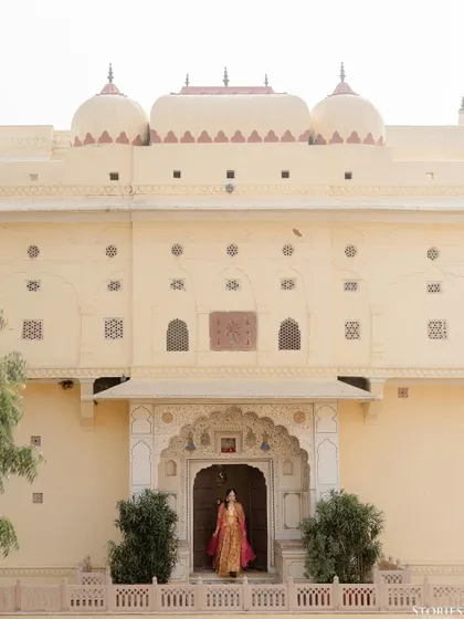 A bride framed by the grandeur of a Jaipur palace. This single shot tells a story of heritage, anticipation, and elegance. My approach is to use the environment to elevate the narrative, making you the central character in a magnificent setting.