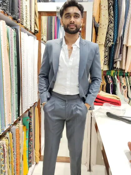 Modern tailoring for the modern man. Here, a client wears a custom-fit light grey peak lapel suit paired with contemporary Gurkha pants, a perfect example of how we can blend classic and unique styles.