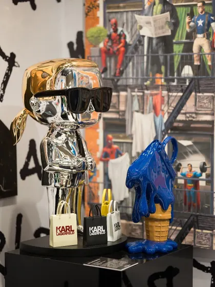 A chrome sculpture inspired by Karl Lagerfeld, complete with his signature sunglasses and shopping bags. This piece is a nod to the intersection of fashion and art, celebrating iconic figures through a pop art lens.