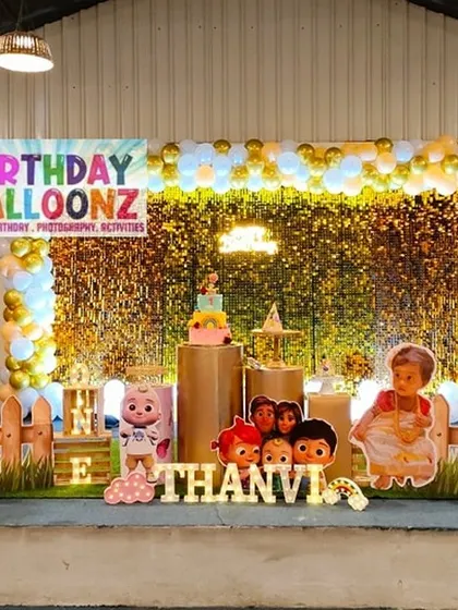 Here is another Cocomelon themed party, this time with a natural leaf wall backdrop and gold balloons. The setup includes cutouts of all the main characters, a personalized chalkboard-style milestone board, and a picket fence for a playful touch.