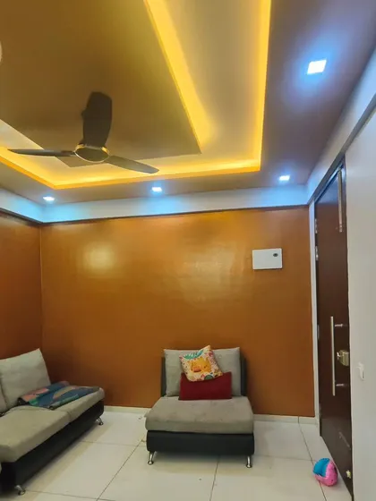 A living room featuring a warm, copper-toned metallic texture on the walls. This finish, combined with the false ceiling lights, creates a cozy and luxurious ambiance.