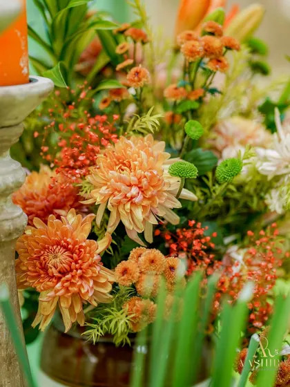 A close-up of a floral arrangement featuring burnt-orange chrysanthemums, creating a warm and textured look.