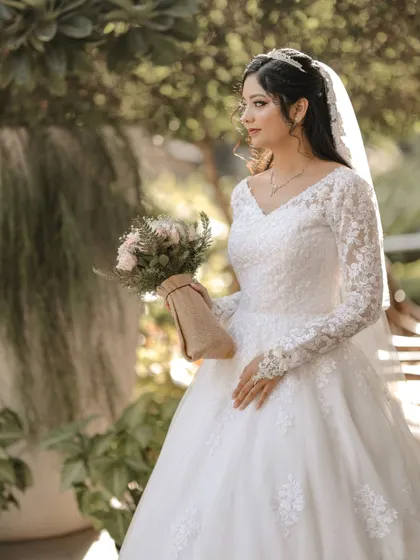 A three-quarter portrait of the bride holding her bouquet in a garden setting.