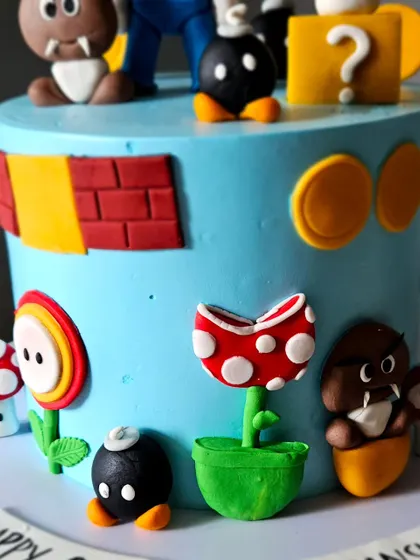 A side view of the Super Mario cake, highlighting the piranha plant, coins, and other iconic elements that wrap around the cake, creating a full 360-degree scene.