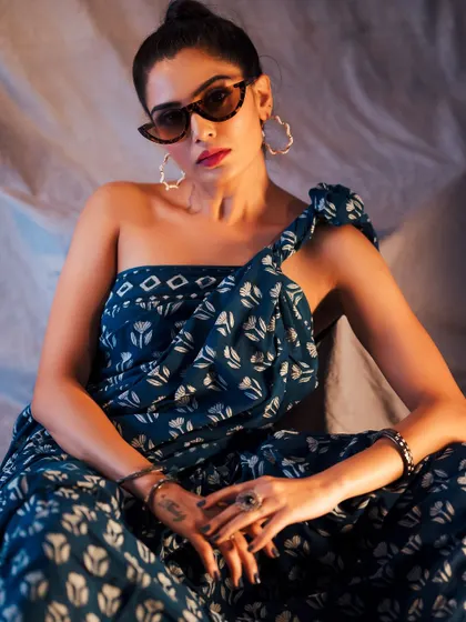 A confident, seated portrait that showcases the full outfit and accessories. The lighting is set to highlight the texture of the saree and the model's pose.