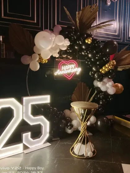 A full view of the 25th anniversary setup, highlighting the placement of the light-up numbers, the balloon arch, and the decorative stand.