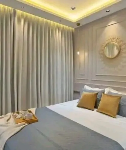A serene bedroom design with wall molding, elegant curtains, and a sunburst mirror, creating a calm and classic ambiance.