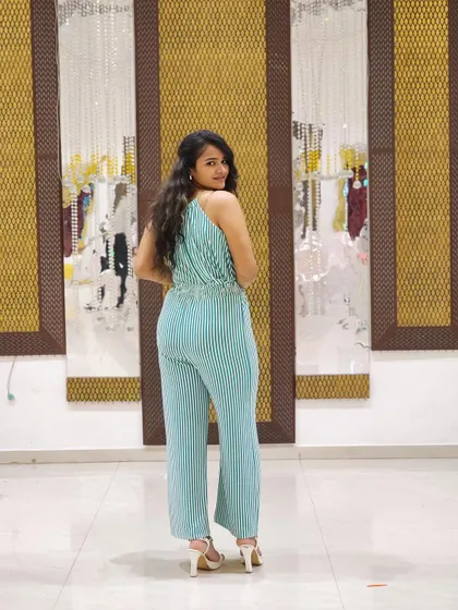 A back view of the jumpsuit, showing the halter-neck detail and the pleated fabric. It's a simple yet stylish look.